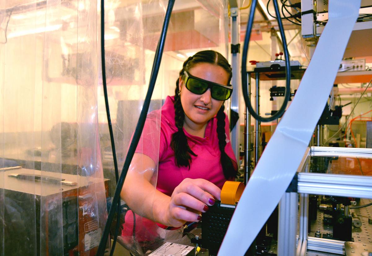 PhD student Alyssa Allende Motz inspects a machine in the engineering physics lab at Mines.